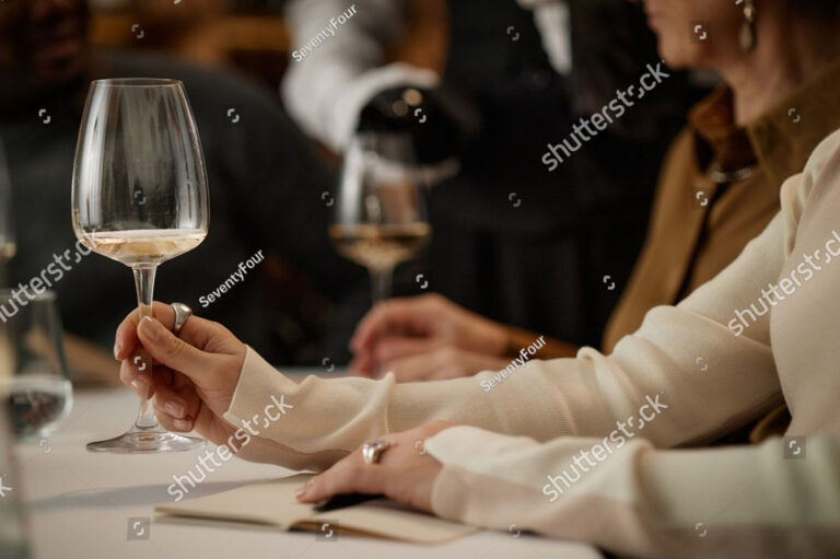 stock-photo-caucasian-young-adult-woman-holding-wine-glass-and-swirling-wine-during-tasting-event-sitting-at-2705951865